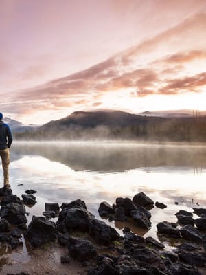slow travel by a man standing on the bank of a calm lake exhibiting mindful RV living